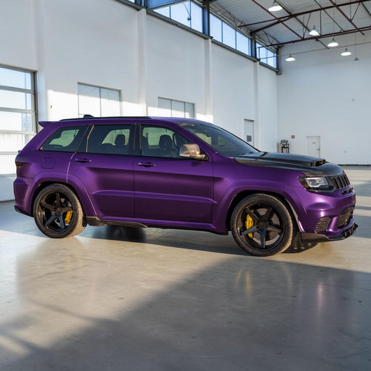 A matte purple Jeep Grand Cherokee with a custom black hood and black wheels, parked inside a bright, modern industrial garage.