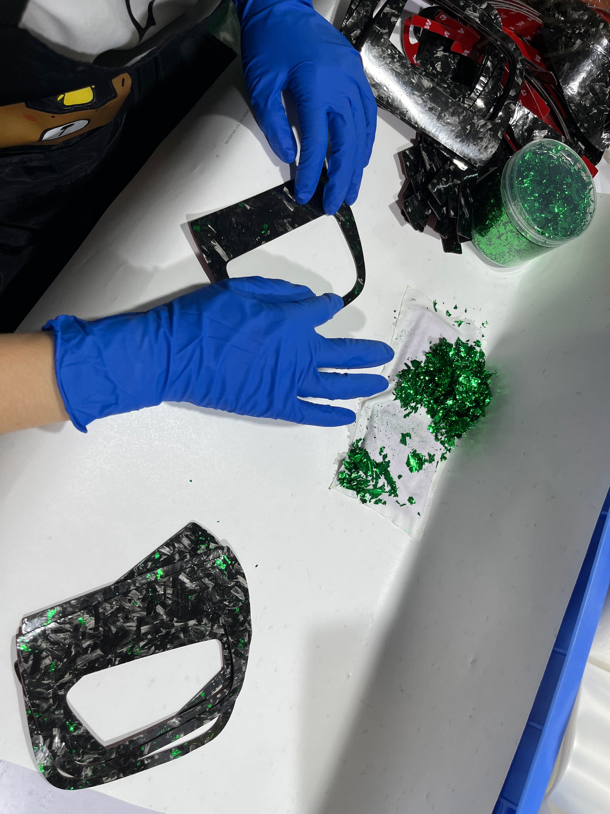 showcases zetacomposites employee applying green flakes to a carbon fiber overlay piece