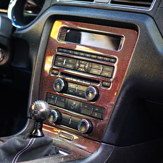 Carbon fiber radio surround trim with red woven texture around audio controls