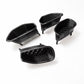Four black carbon fiber textured automotive air intake or vent components arranged on a plain white background.