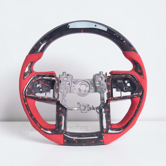 Carbon fiber steering wheel with red grips, black spokes, and center control plate