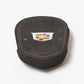 A dark gray suede or microfiber car airbag  cover featuring a metallic Cadillac crest emblem in the center, red contrast stitching, and the word 'AIRBAG' printed below.