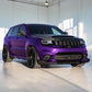 A purple and black custom-decorated Jeep Grand Cherokee is parked in a bright, modern indoor showroom with concrete floors and white walls.