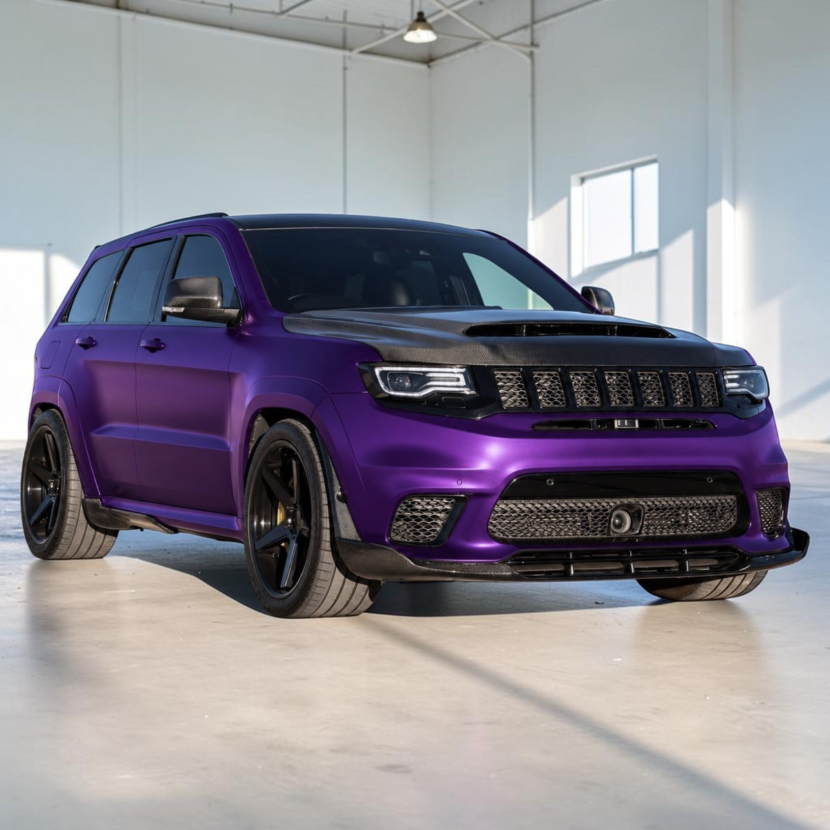 A purple and black custom-decorated Jeep Grand Cherokee is parked in a bright, modern indoor showroom with concrete floors and white walls.