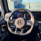 Carbon-fiber steering wheel upgrade with tan center pad and Mercedes logo