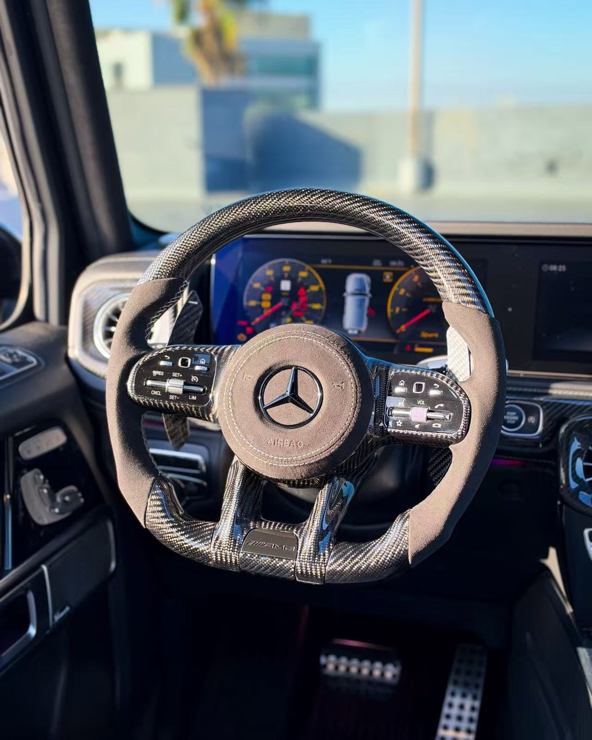 Carbon-fiber steering wheel upgrade with tan center pad and Mercedes logo